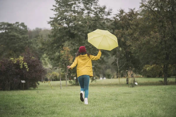 Cute mulatta with yellow umbrella running and having fun — Stock Photo, Image