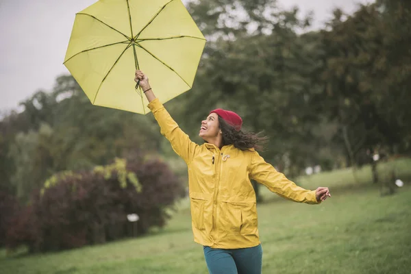 Cute mulatta with yellow umbrella feeling happy — Stock Photo, Image