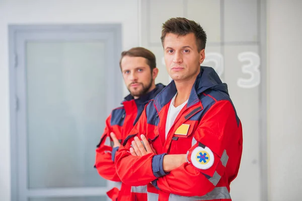 Two medical workers in red uniform looking determined — Stock Photo, Image