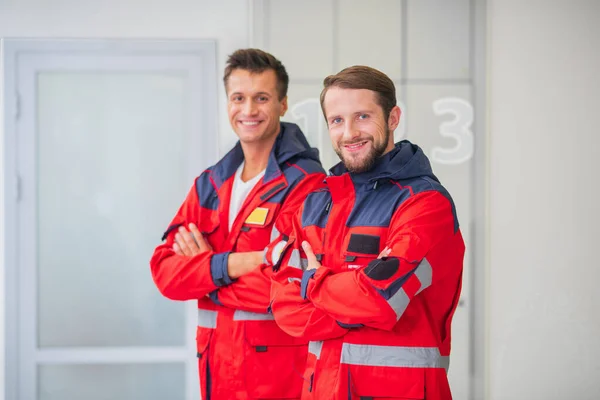 Zwei Ärzte in roter Uniform stehen mit verschränkten Armen — Stockfoto