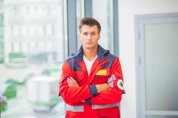 Médico varón de uniforme rojo de pie cerca de la ventana — Foto de Stock