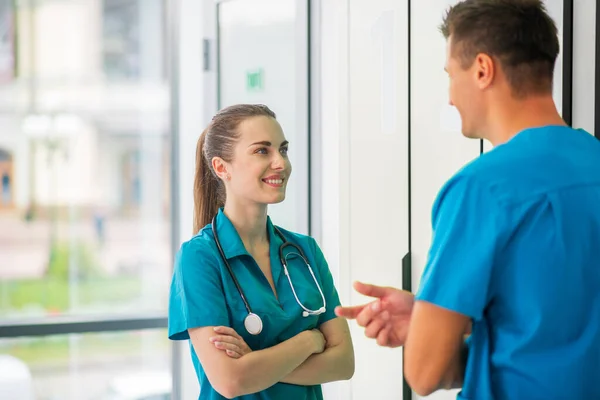 Bastante joven doctora en uniforme azul hablando con un colega — Foto de Stock