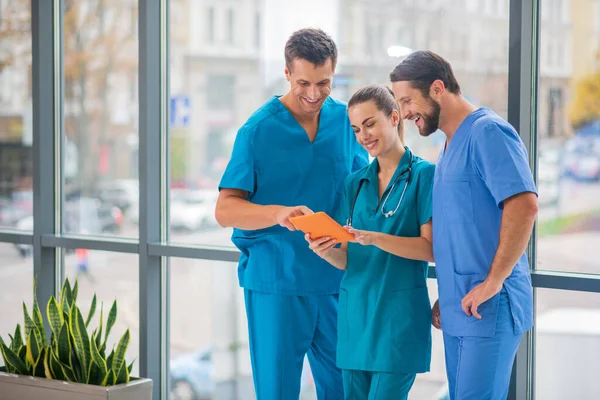 Grupo de médicos viendo algo en la tableta y mirando involucrados — Foto de Stock