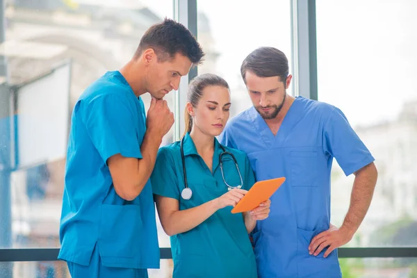 Група лікарів дивиться щось на планшет і виглядає серйозно — стокове фото