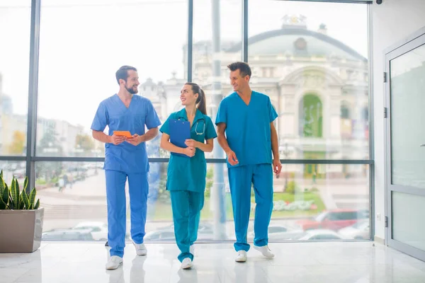 Three doctors walking in the corridor and talking — Stock Photo, Image