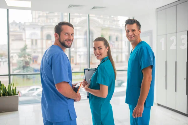 Tři doktoři, kteří mají pracovní den na klinice a vypadají sebejistě — Stock fotografie