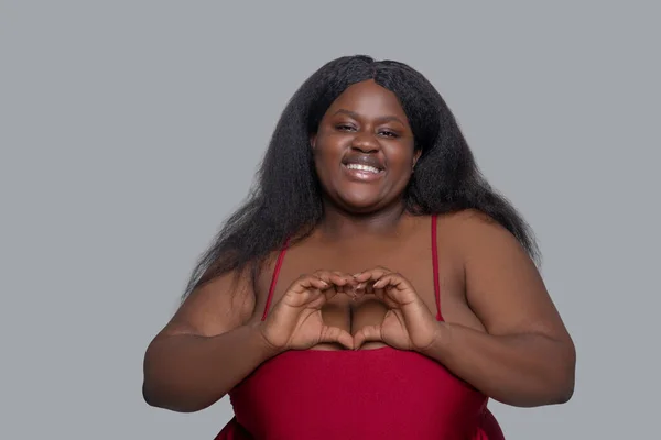Afroamerykanka młoda kobieta w czerwonej bieliźnie pokazuje znak serca — Zdjęcie stockowe