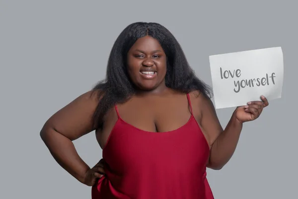 Leende afrikansk amerikansk ung kvinna i röda underkläder agiterar för egen kärlek — Stockfoto