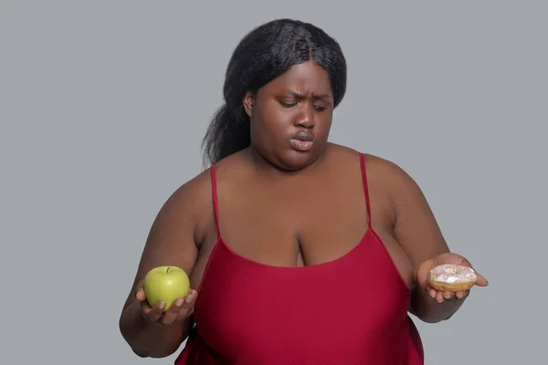 Donna afroamericana con una mela e ciambelle in mano — Foto Stock