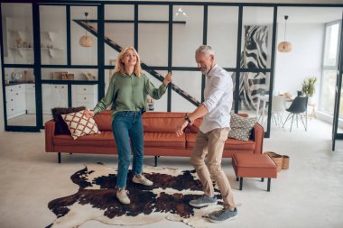 Kadın ve erkek odada dans ediyor ve enerjik görünüyorlar.