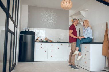 Kadın ve erkek mutfakta konuşuyor ve ilgileniyorlar.