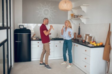 Erkek ve kadın mutfakta eğleniyor ve şarkı söylüyorlar.