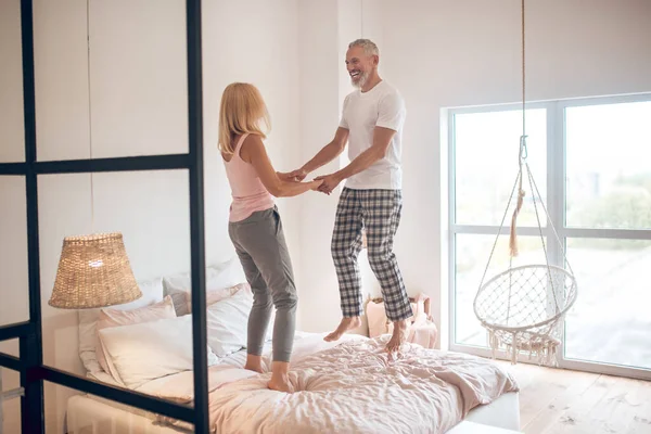 Pareja madura saltando en la cama y sintiéndose increíble — Foto de Stock