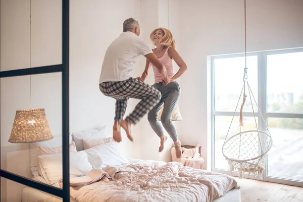 Mature couple jumping on the bed and feeling awesome — Stock Photo, Image