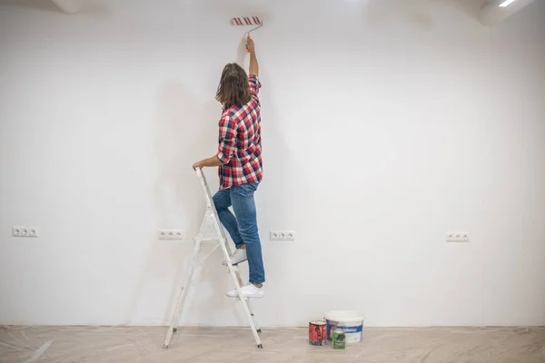 Young man in checkered shirt painting the wall — Stock Photo, Image