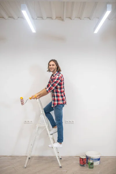Mladý muž v kostkované košili malování stěny — Stock fotografie