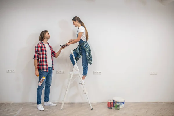 Joven mujer de pie en escalera y el hombre ayudándola a bajar — Foto de Stock