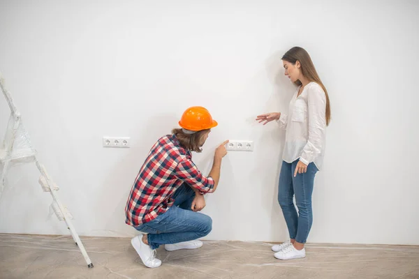 Female purchaser talking to the construction worker and looking unpleased — Stock Photo, Image