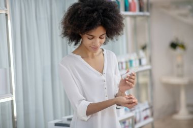 Genç kız krema tüpüne bakıyor.