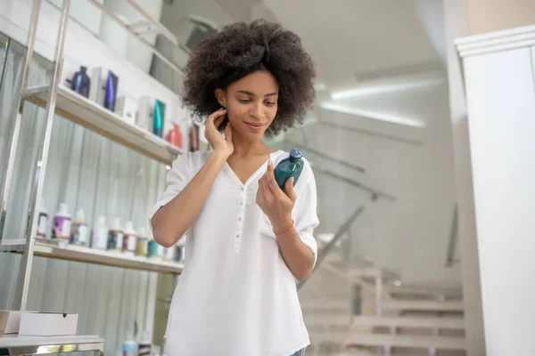 Zufriedenes Mädchen mit Kosmetikprodukt in der Flasche — Stockfoto