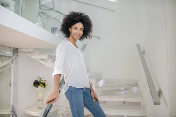 Young stylish girl standing on stairs indoors — Stock Photo, Image