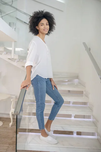 Happy slender woman leaning on railing on stairs — Stock Photo, Image