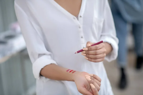 Mani femminili che provano fodera labbra rosse sul polso — Foto Stock