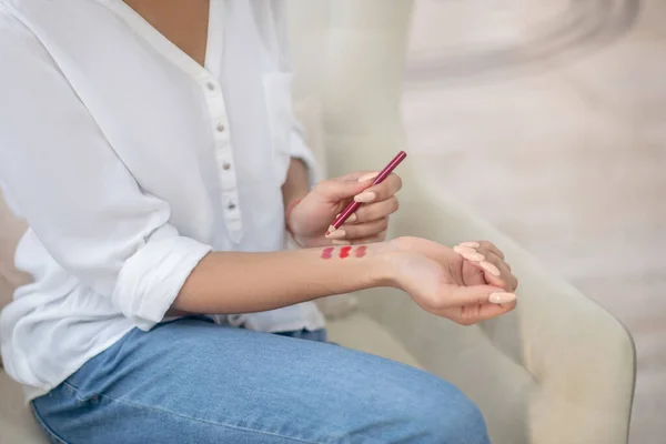 Mujer probando diferentes tonos de lápiz labial rojo — Foto de Stock