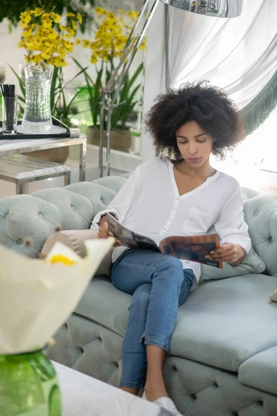 Ενδιαφέρουσα γυναίκα με περιοδικά στον καναπέ — Φωτογραφία Αρχείου