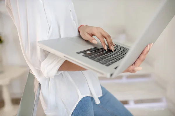 Female hands holding open laptop without face