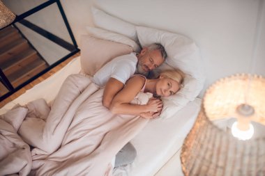 Evli çift yatakta uyuyor ve huzurlu görünüyorlar.