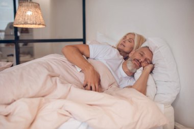 Evli çift bir yatakta huzur içinde uyuyor.