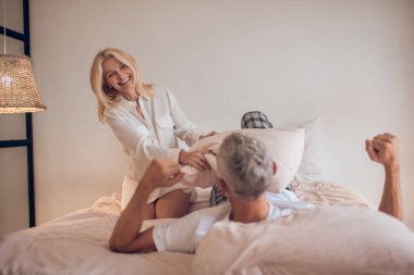 Evli çift yatak odasında eğleniyor ve neşeli görünüyorlar.