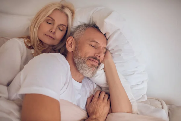 Супружеская пара спит на кровати и выглядит мирно — стоковое фото