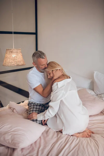 Grey-haired man hugging a blonde woman and looking romantic — Stock Photo, Image