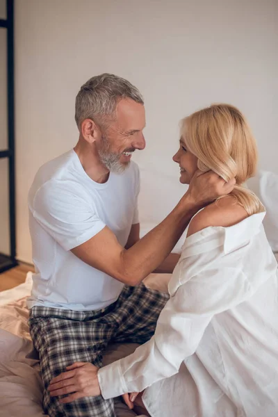 Homem de cabelos grisalhos abraçando uma mulher loira e sorrindo — Fotografia de Stock