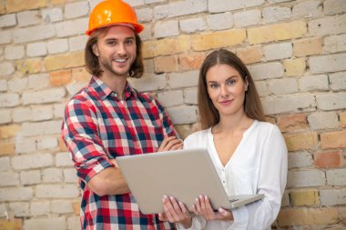 Koruyucu kasklı genç bir adam ve internetten bilgi arayan bir kadın müşteri.