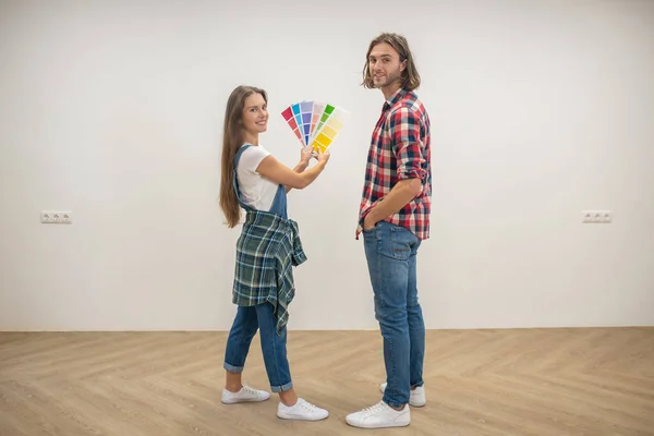 Jovem segurando uma paleta de cores e discutindo a cor das paredes com seu namorado — Fotografia de Stock