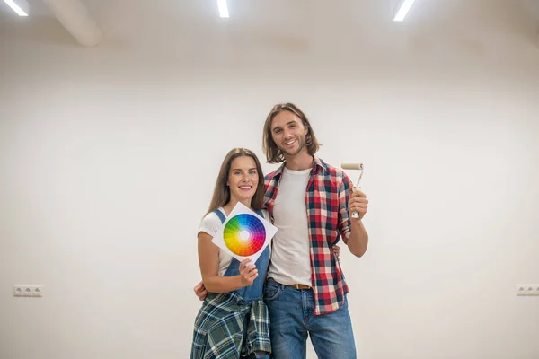 Молодая пара обсуждает цвет стен и выглядит счастливой — стоковое фото