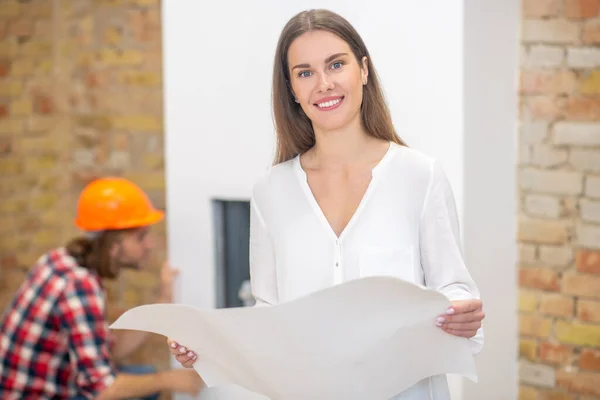 Mujer joven con camisa blanca escrutando el diseño del proyecto — Foto de Stock