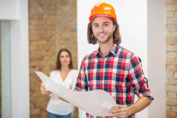 Joven con casco protector sosteniendo el diseño del proyecto —  Fotos de Stock