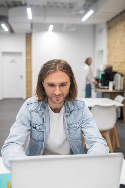 Jonge man met blond haar die achter de laptop zit en er geconcentreerd uitziet — Stockfoto