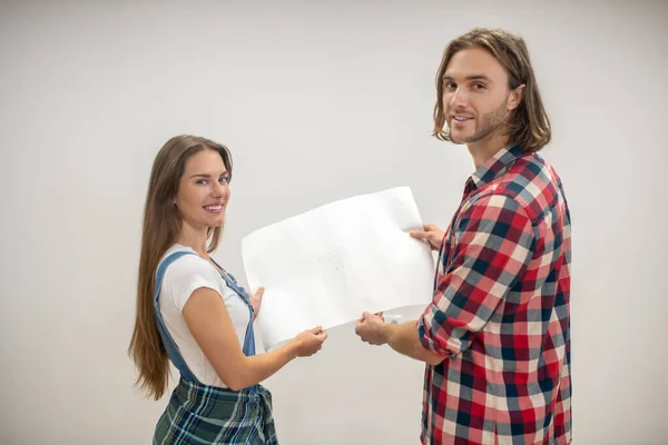 Par holder en tegning af hjem design projekt og smilende - Stock-foto