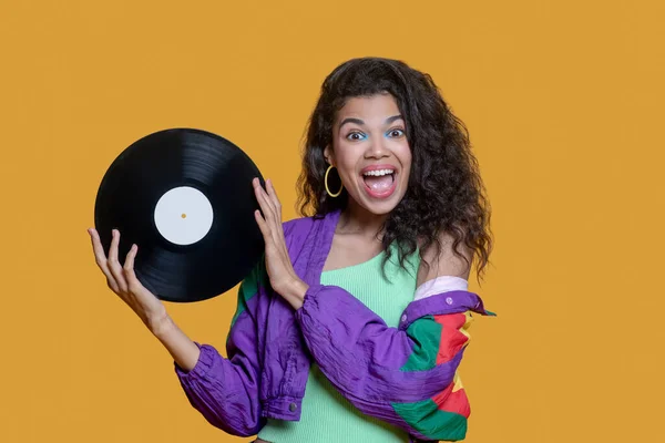 Cute dark-haired young girl holding a record and feeling excited — Stock Photo, Image