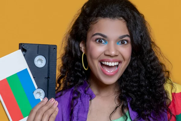 Ganska mörkhårig ung flicka med videokassett ser glad ut — Stockfoto