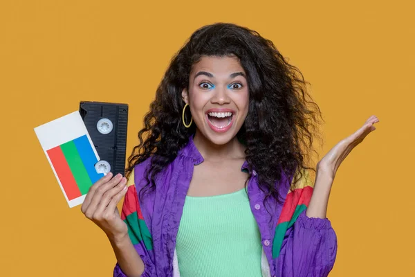 Pretty dark-haired young girl with video cassette looking excited — Stock Photo, Image