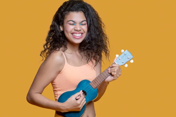 Pretty dark-haired young girl in yellow clothes with ukulele — Stock Photo, Image