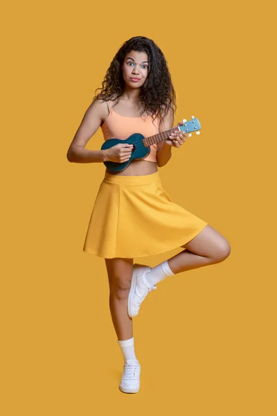Söt ung flicka i gula kläder med ukulele — Stockfoto