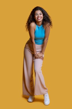 Koyu renk saçlı, mavi bluzlu genç kadın harika hissediyor.