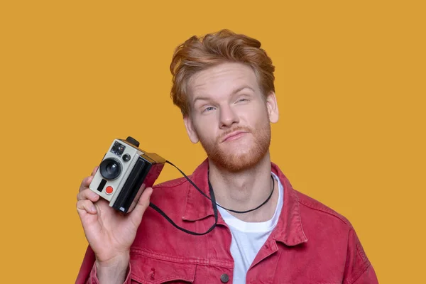 Red-haired bearded young man with old camera looking thoughtful — Stock Photo, Image